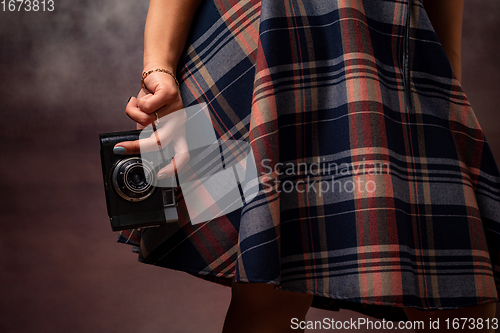 Image of Girl\'s hand holding a camera at the hem of the dress, studio photography on a gray background