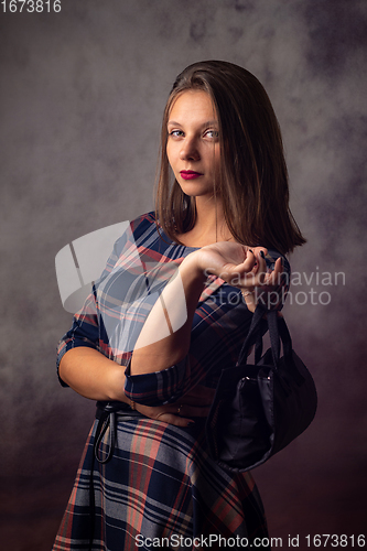 Image of Portrait of a beautiful girl with a black handbag in her hands