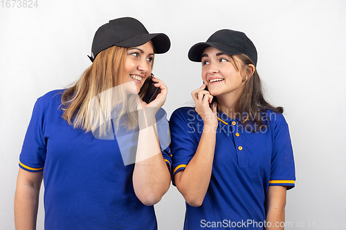 Image of Mother and daughter are standing with their backs to each other, talking on the phone and looking at each other