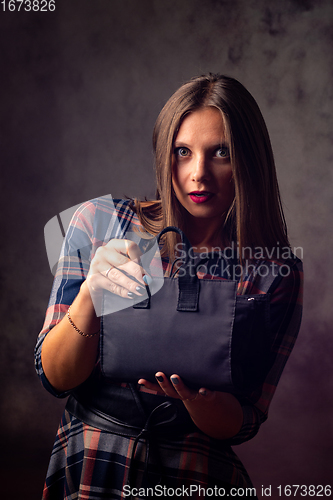 Image of A beautiful girl holds a handbag in front of her and looked into the frame with big eyes