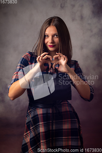 Image of Portrait of a beautiful girl on a gray background, the girl holds a black handbag in front of her