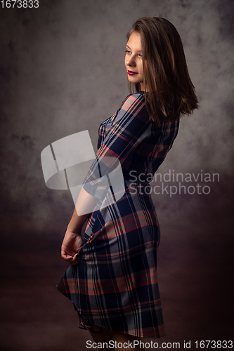 Image of Portrait of a beautiful girl in a checkered dress, the girl is turned sideways