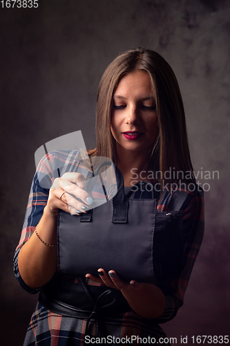 Image of A beautiful girl holds a handbag in front of her and mysteriously opens it