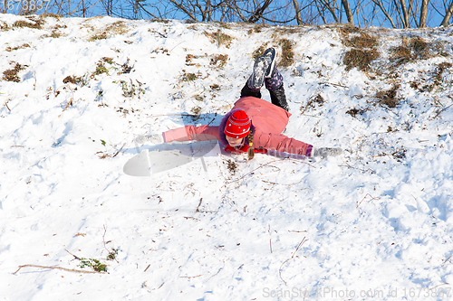 Image of A girl is rolling down a snow-covered slide upside down