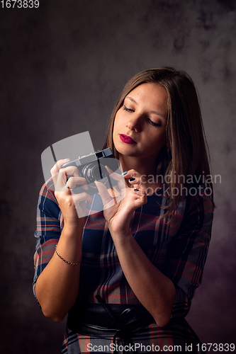 Image of Girl photographer adjusts the camera, studio photography on a gray background