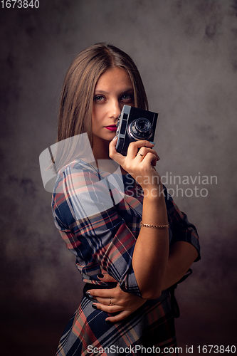 Image of Girl photographer holding an old camera in her hands, studio photography on a gray background