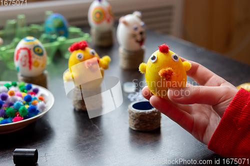 Image of The child made a figurine of a chicken from an egg and shows it into the frame, in the background other figures