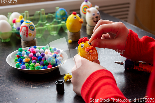 Image of A child glues an eye to the shape of a chicken for Easter