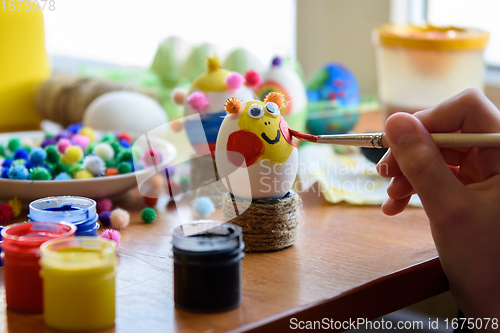 Image of Child\'s hand draws a funny face on Easter egg