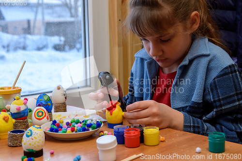 Image of A girl glues a decorative element to a craft with a glue gun