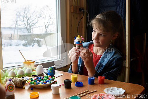Image of The girl carefully examines the chicken egg craft