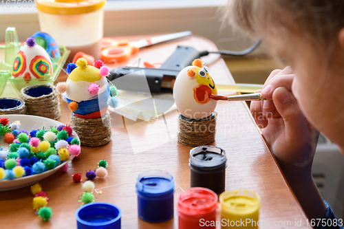 Image of Girl carefully and neatly paints Easter eggs, close-up