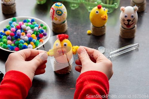 Image of Children\'s hands made a chicken craft out of an egg, there are other figures in the background