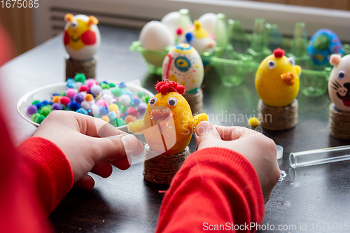 Image of The child finishes making another egg-shell figurine to celebrate Easter