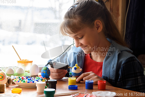 Image of A girl glues elements to crafts with a glue gun