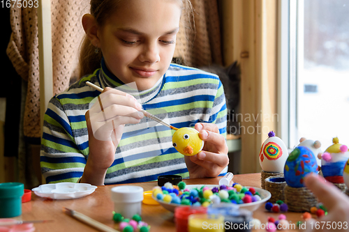 Image of A twelve-year-old girl paints Easter eggs for the holiday