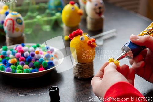 Image of Children\'s hands apply glue to the egg craft element