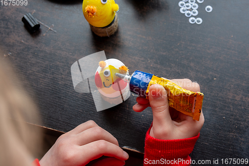 Image of A girl decorates an egg for easter and glues funny eyes to it
