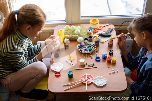 Image of Two girls at the table are painting Easter eggs