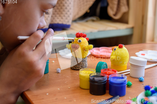 Image of Girl gently paints Easter eggs with a brush and paints