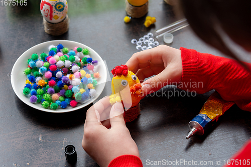 Image of A girl glues wings to a chicken figurine made from an egg