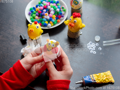 Image of The girl is holding a beautifully painted egg with a smiling painted face