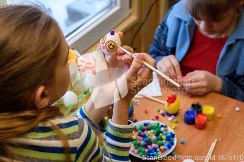Image of Children at the table are painting Easter eggs for the holiday