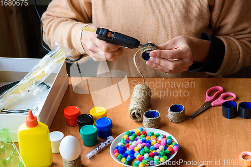 Image of Girl\'s hands decorate crafts using twine and hot melt glue, top view