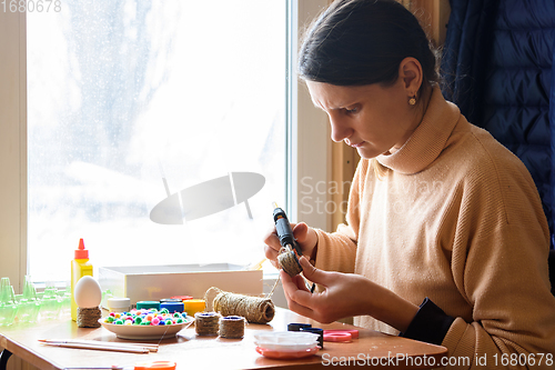 Image of Girl decorates crafts while sitting at home by the window