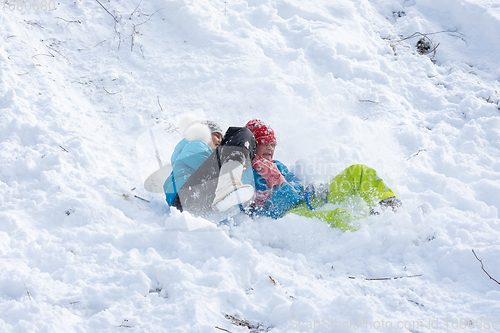 Image of Two girls slide down a slide into a snowdrift