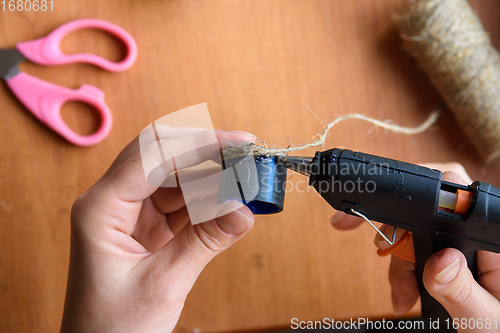 Image of Girl\'s hands decorate crafts using twine and hot melt glue, close-up