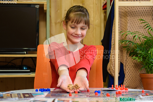 Image of A girl throws large dice making another move while playing a board game at the table