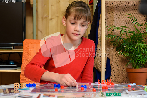 Image of A girl makes another move with chips while playing a board game at the table