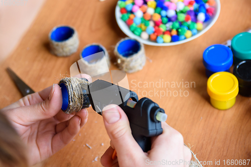 Image of The girl\'s hands make crafts from twine and a glue gun