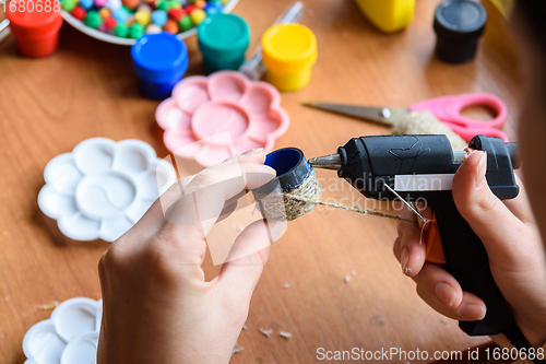 Image of The girl\'s hands apply hot melt glue to the elements of the craft, gluing twine