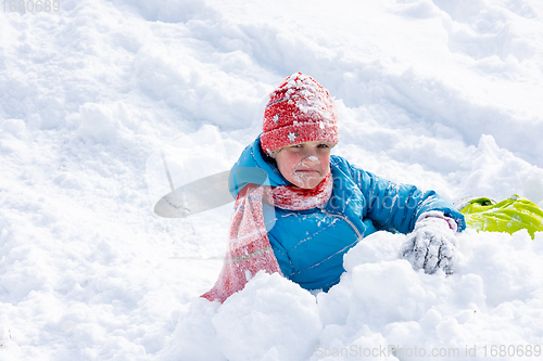 Image of The girl who rolled down the hill has all her face in the snow, the girl looks funny into the frame