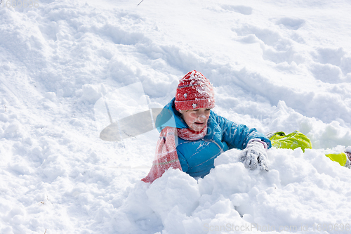 Image of The girl who rolled down the hill has all her face and a hat in the snow