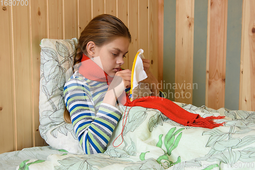 Image of Sick girl lying in bed doing embroidery on the hoop