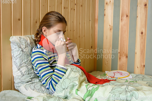 Image of Sick girl drinking tea while sitting in bed