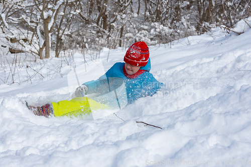 Image of The girl slid down the hill into a snowdrift and squeezed her eyes from the snow flying into her face