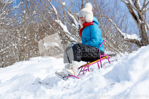 Image of Girl sledding downhill in winter