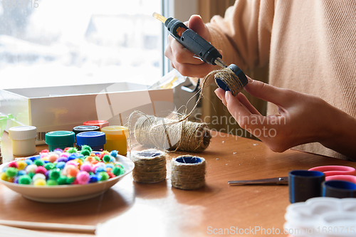 Image of Girl\'s hands decorate crafts using twine and hot melt glue