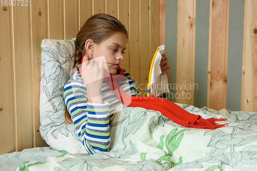 Image of Sick girl lying in bed is embroidering on the hoop