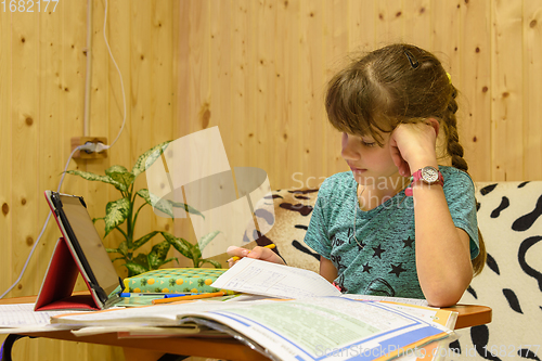 Image of Girl teaches lessons at the table at home