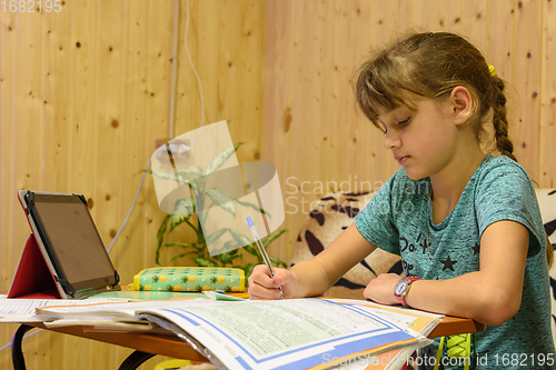 Image of Girl doing homework in the interior of a country house room