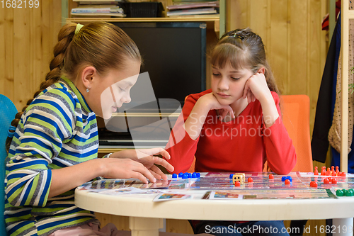 Image of A girl explains to another girl how to play a board game