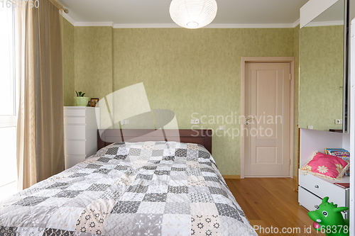 Image of Bedroom interior with a large double bed and a wardrobe with a mirrored door