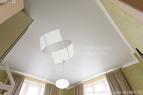 Image of Stretch white matte ceiling close-up with a chandelier in the interior of a living bedroom