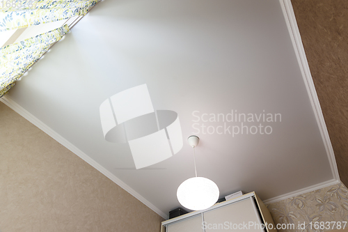 Image of Stretch white matte ceiling close-up with a chandelier in the interior of a rectangular room