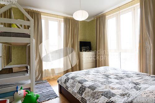 Image of Bedroom interior with large double bed, bunk cot and two large stained glass windows